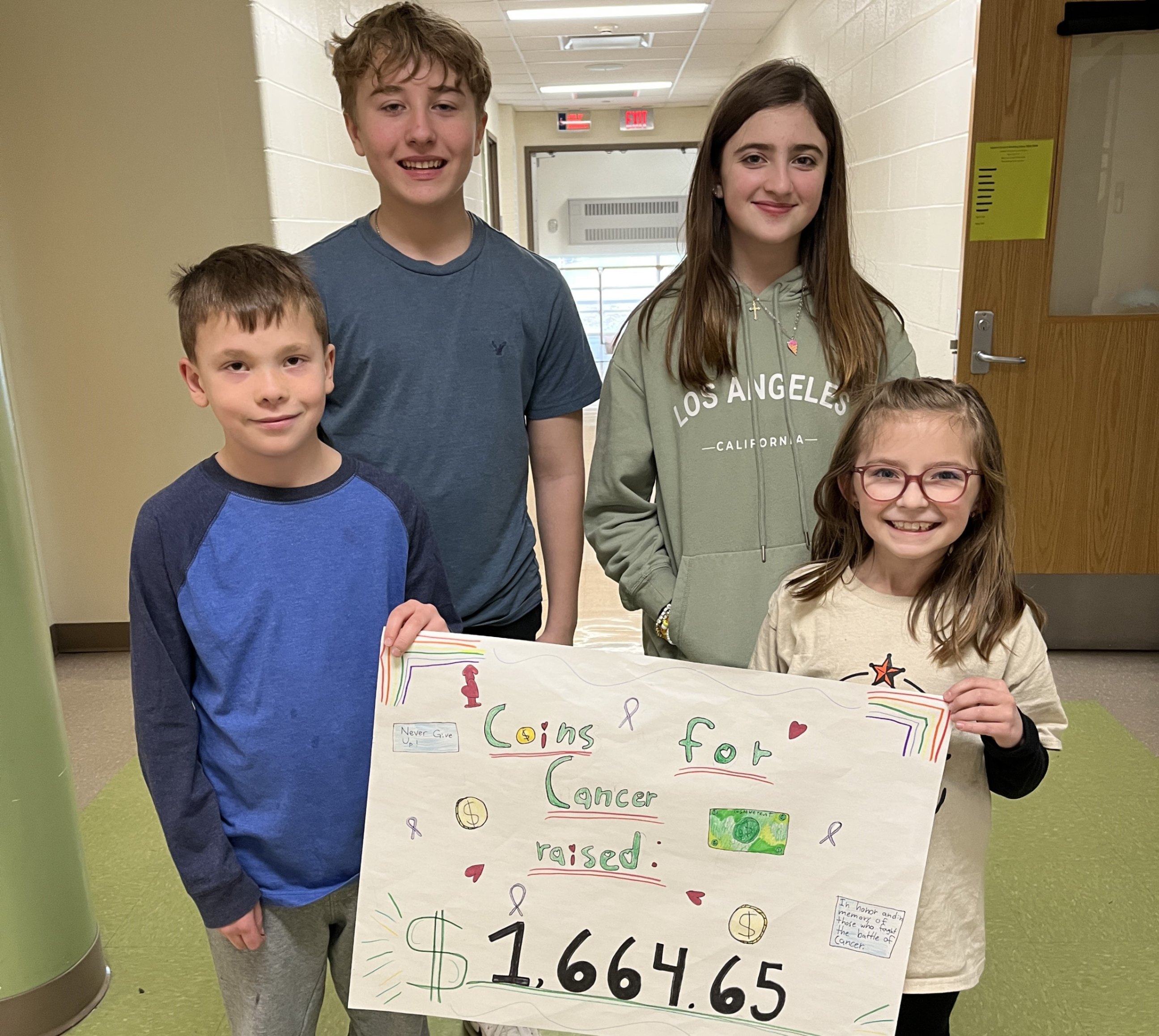 Students Perry Butcher, Chael Radaker, Natalie Stoltzfus and Melanie Stoltzfus display a sign with the amount of money raised for the American Cancer Society.